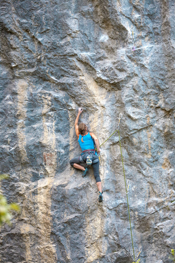 女孩爬上岩石。 登山者正在训练攀登岩石。 一个强壮的运动员克服了一条艰难的攀登路线。 极端的爱好。 一个女人在大自然中参加运动。