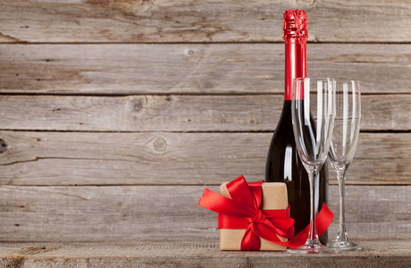情人节贺卡与香槟和礼品盒前面的木墙。 为你的问候留出空间