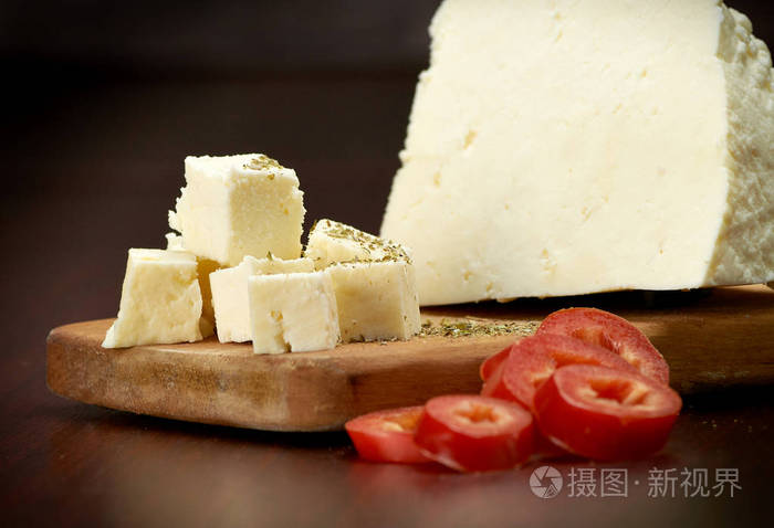 一片精致的白奶酪和红甜椒放在木板上深色背景特写镜头