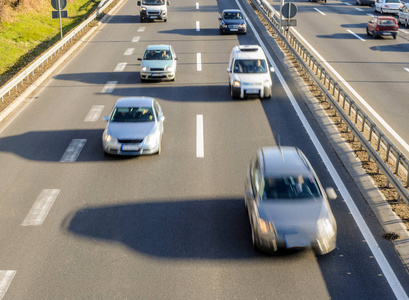 汽车在高速公路上快速行驶的鸟瞰图，有三条车道和道路围栏屏障