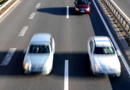 汽车在高速公路上快速行驶的鸟瞰图，有三条车道和道路围栏屏障