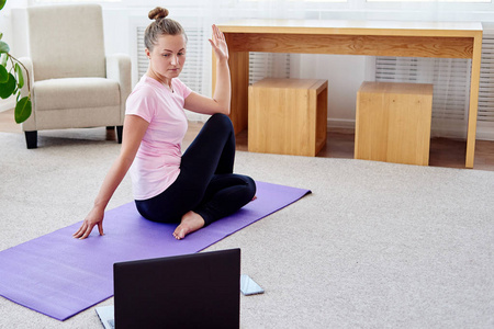 年轻女子在家里练习瑜伽，室内复制空间。 女孩坐在一半的鱼王锻炼阿达马森德拉萨纳姿势全长。 健康和健康的生活方式