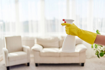 s hand in yellow protective glove holding white spray bottle wit