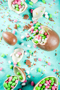 五颜六色的春天复活节糖果背景，巧克力鸡蛋，糖洒和棉花糖兔子，绿松石浅蓝色混凝土背景复制空间顶部视图。