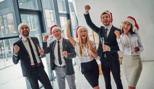 圣诞快乐，新年快乐一群上班族一起在工作中庆祝寒假。商务人士在办公室喝香槟。