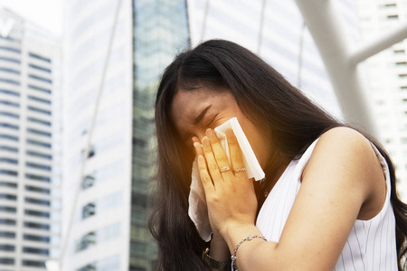 美丽的女人因流感或天气变化而打喷嚏。