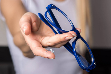 柔软的隐形眼镜和蓝色镶边眼镜在美丽的女性手中。