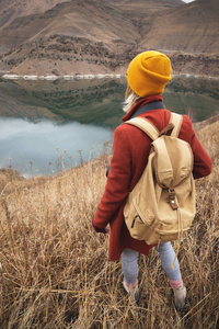 秋天或初春, 一位女旅行者在山上的一个湖的背景上的画像。旅游理念