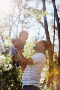 父亲和儿子在森林里玩耍，阳光从树上照进来