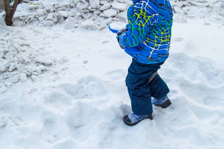 迷人的小男孩在冬天挖雪蓝小铲子。