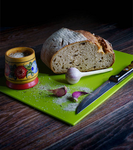 家做的好吃的面包放在白色的餐巾纸上，或者放在木板上，或者放在绿色的木板上，盐，大蒜，刀子上