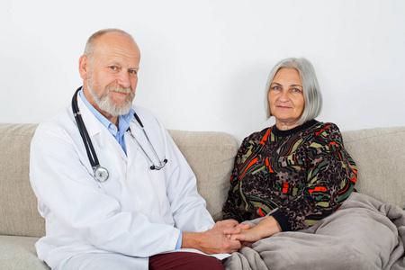 老年男性医生检查坐在沙发上的老年妇女季节性流感家庭护理
