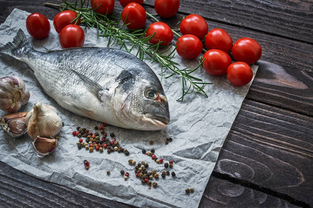 地中海海鲜概念。 生的多拉多鱼，大蒜，西红柿，胡椒和迷迭香在旧的木桌上。 新鲜有机海或多拉达鱼。 顶部视图复制空间