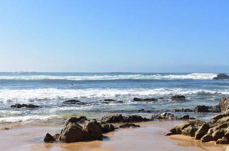 有岩石的野生海滩，有泡沫和薄雾的巨浪。 蓝天晴天加利西亚西班牙。