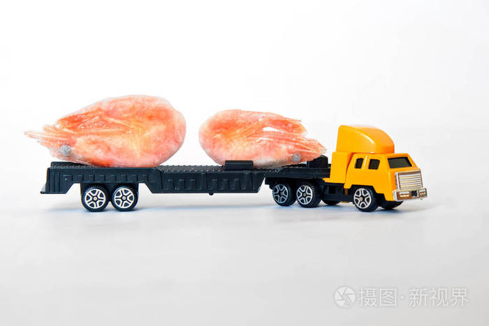 一辆玩具卡车载着一对冷冻虾。 海鲜送货。 健康的食物。 白色背景。