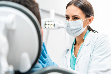 戴口罩的女牙医在牙科诊所看病人