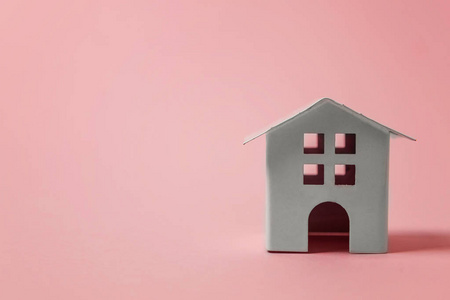 简单的设计与微型白色玩具屋隔离在粉红色粉彩色彩的时尚背景。 抵押财产保险梦想家居概念。 复制空间