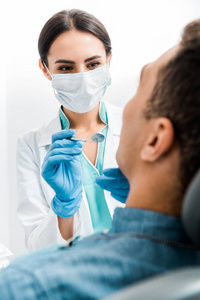 女性口腔医生在乳胶手套和面罩中的选择性聚焦检查非裔美国人患者