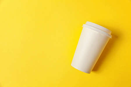 简单的平躺设计纸咖啡杯上的黄色五颜六色的时尚背景。 外卖饮料容器。 早上好，醒来的概念。 饮料模型的模板。 顶部视图复制空间