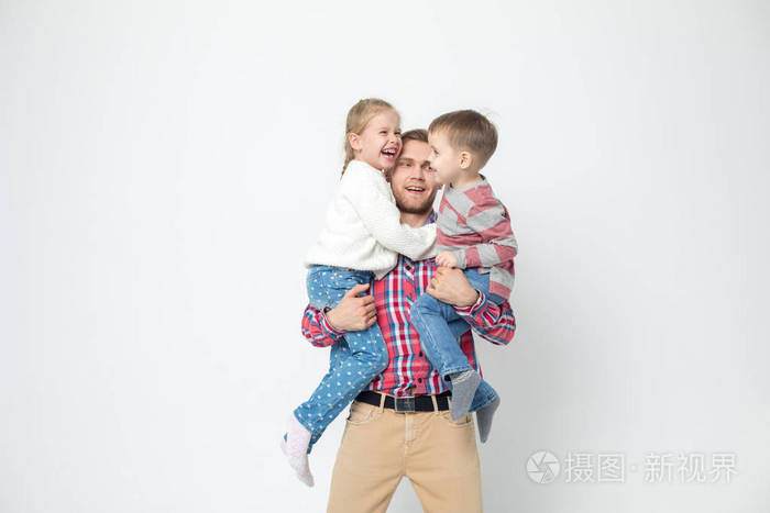 父亲带着孩子在白色的背景上玩得很开心。父亲抱着女儿和儿子