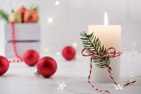 圣诞家居装饰。 燃烧的白色蜡烛和圣诞节室内红色装饰品