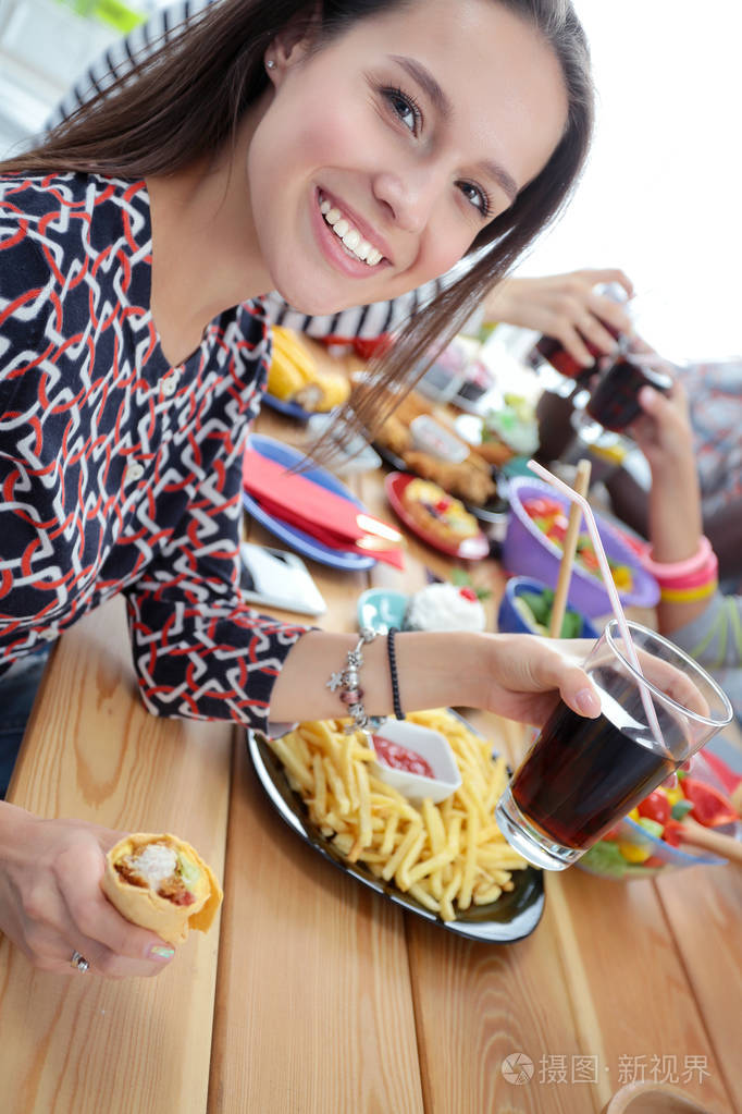 顶视图的一群人在一起时坐在木桌吃饭.在桌子上的食物.人们吃快餐
