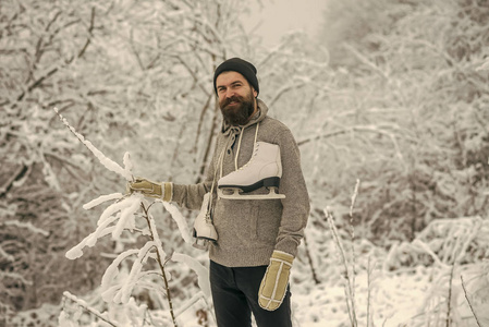 有胡子的人在雪地森林里带着冰鞋。 穿热夹克的人冬天胡须很暖和。 冬天的护肤和胡须护理。 温度冻结，寒冷，突然下雪。 冬季运动和休