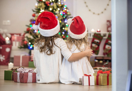 两个带礼物的小女孩围着圣诞树