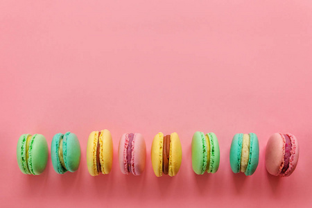 蓝色,黄色,绿色,马卡龙或马卡龙甜点蛋糕隔离在时尚的粉红色粉彩背景