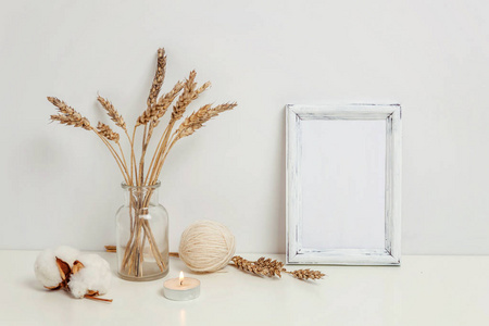 垂直框架模型与野生黑麦花束在玻璃花瓶附近的白色墙壁。空帧模拟演示设计。现代艺术的模板框架。斯堪的纳维亚风格自然生态家居装饰
