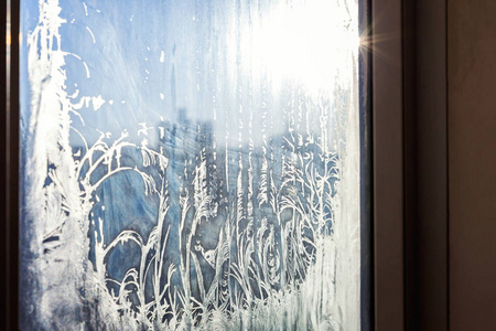 冰冻的冬季窗户，有着闪亮的冰霜图案纹理。圣诞奇观符号，抽象背景..极北低温，冰天雪地，寒冷的冬季室外