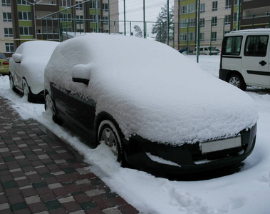 天气不好，黑车在新房子的背景上覆盖着雪。