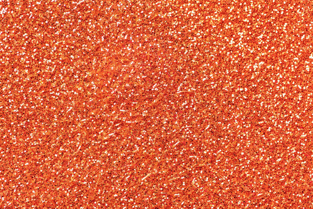 明亮的橙色闪闪发光的背景从小亮片特写。 来自纺织品的明亮闪亮的背景。 闪烁的珊瑚纸
