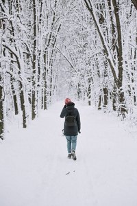 在白雪皑皑的冬季公园里散步的女人的后景
