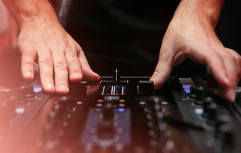 DJ在嘻哈音乐晚会上播放音乐。专业的声音混合控制器数字混合器技术，用于光盘骑师刮取乙烯基记录和混合曲目