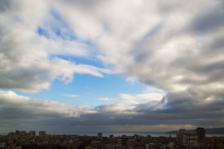 海滨城市的戏剧性云景。 乌云围绕着白天蓝天的最后一点。