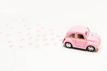 粉红色复古玩具车提供粉红色背景的心盒。2月14日情人节卡片。送花。3月8日, 国际妇女节快乐