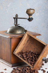混凝土背景上的旧木制咖啡研磨机