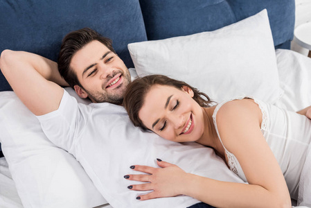 美丽的微笑的夫妇在家里的床上拥抱