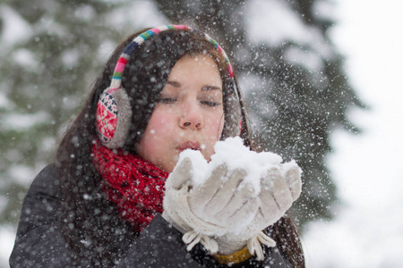 一个少女在冬天用手吹着蓬松的雪