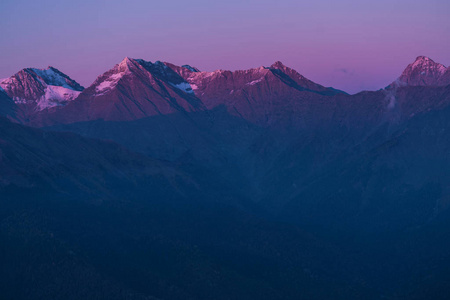 s rays illuminate the tops of the mountains. Snow on mountain pe