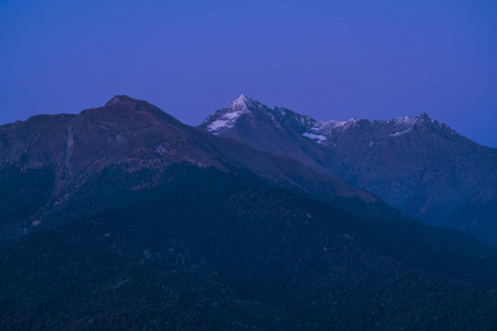 夕阳下的群山。 紫色的山峰和深蓝色的天空。 山峰上的雪