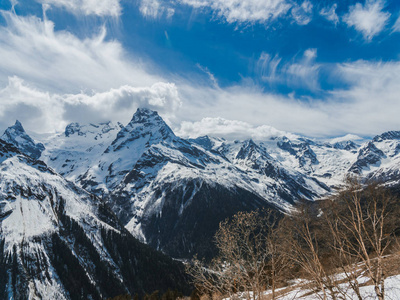 覆盖着雪的山峰。 雪山上阳光明媚的一天。 山顶上方的云。 美丽的山脉