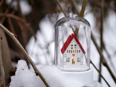 小玩具装饰白色房子，有红色的屋顶，在白雪覆盖的树上点燃照明，冬季季节性假日圣诞节的概念，新年的新家，家庭舒适。