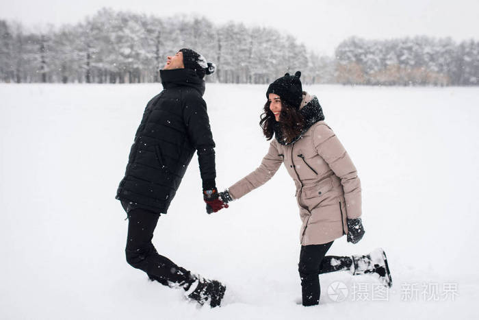 恋爱中的情侣在白雪皑皑的树林里散步
