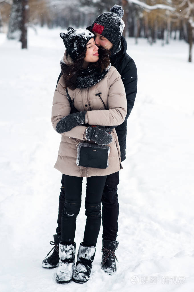 恋爱中的情侣在白雪皑皑的树林里散步