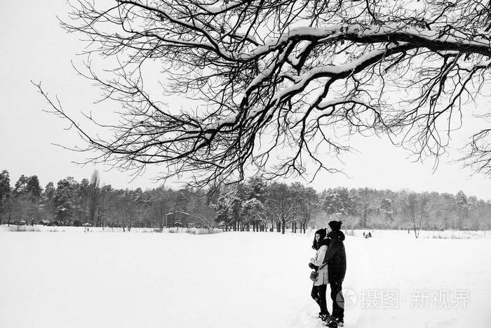 恋爱中的情侣在白雪皑皑的树林里散步
