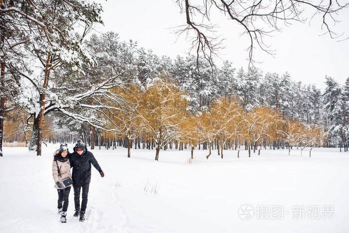 一对相爱的情侣在雪地森林里散步