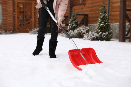 年轻女子在她家附近用铲子擦雪