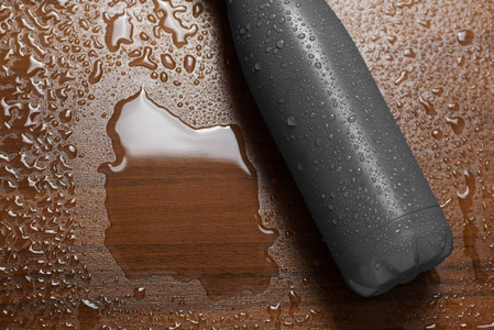 不锈钢热水瓶隔离在木制桌子上，喷水。 黑色颜色